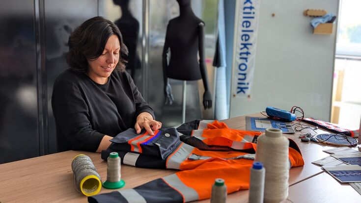 ENAMEL-Projektleiterin Prof.in Dr.in Anne Schwarz-Pfeiffer mit einer smarten Jacke. Das eingenähte Garn leuchtet. Wie sich solche textilen Komponenten sicher verkapseln lassen, ist Aufgabe des FTB im Rahmen des Förderprojekts.